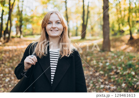 Portrait of pretty young 30s woman in evening autumn sun, smiling. Autumn landscape, calmness, tranquility concept. Pretty female on nature background. High quality photo. Portrait of pretty young 30s woman in evening autumn sun, smiling. Autumn landscape, calmness, tranquility concept. Pretty female on nature background. High quality photo. 129461613