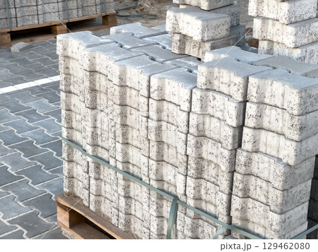 Rows of concrete blocks neatly stacked on wooden pallets at a construction site under clear skies, showcasing organization and readiness for use 129462080