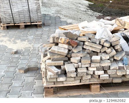 Construction materials are piled up on a paved surface at a building site, showcasing preparation for upcoming work 129462082