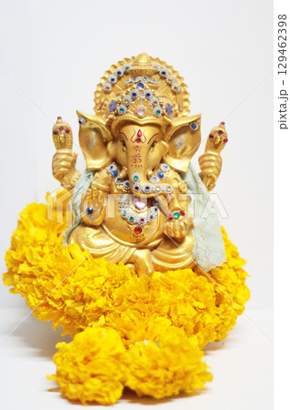 Gold Ganesha Statue god is the Lord of Success God of Hinduism on Marigold flowers Isolated on white background. Gold Ganesha Statue god is the Lord of Success God of Hinduism on Marigold flowers Isolated on white background. 129462398
