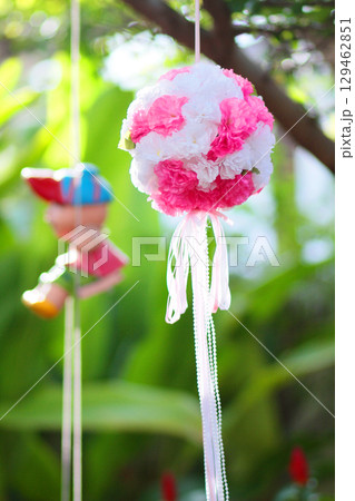 Artificial Pink flowers Hanging and Clay doll decoration on tree in marriage. Wedding decorative in the green garden outdoor. Artificial Pink flowers Hanging and Clay doll decoration on tree in marriage. Wedding decorative in the green garden outdoor. 129462851