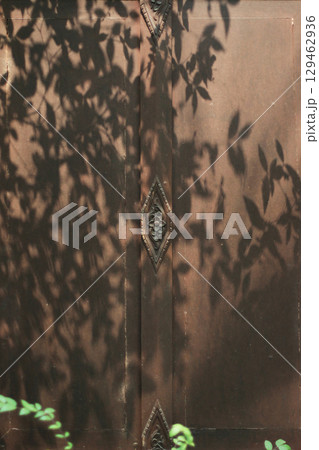 Tree shadows in the garden on antique thai style wooden window on brick wall. Vintage concept. 129462936