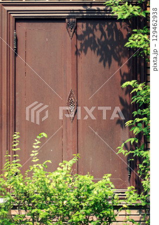 Tree shadows in the garden on antique thai style wooden window on brick wall. Vintage concept. 129462938