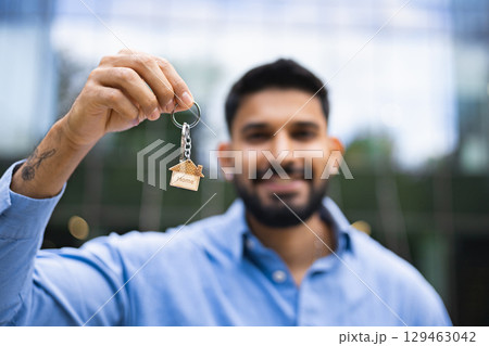 A man holding a house key, symbolizing homeownership and real estate. A man holding a house key, symbolizing homeownership and real estate. 129463042