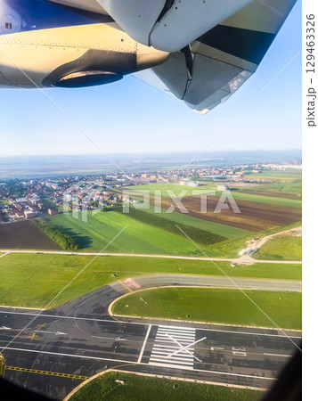 View through airplane window showing engine and runway during boarding. Travel experience, perspective, and anticipation before takeoff. 129463326