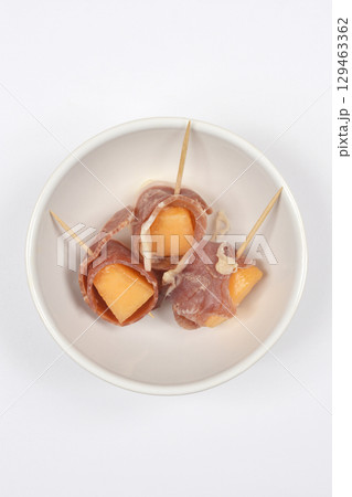 Cubes of melon wrapped in prosciutto Cubes of melon wrapped in prosciutto 129463362