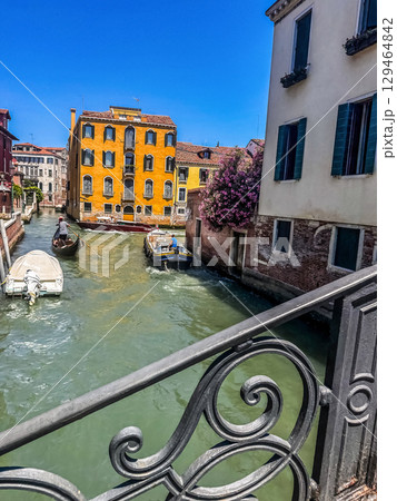 Boats passing along a narrow canal between colorful historic buildings in Venice, Italy.. High quality photo Boats passing along a narrow canal between colorful historic buildings in Venice, Italy.. High quality photo 129464842