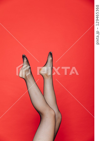 female legs in black tights stockings on a red background female legs in black tights stockings on a red background 129465368