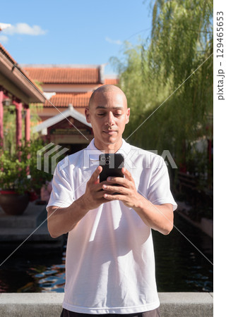 Modern man in Zen garden using smartphone, blending nature and technology 129465653