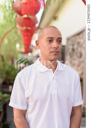 Stylish man in white polo shirt posing in tranquil Zen garden portrait 129465660