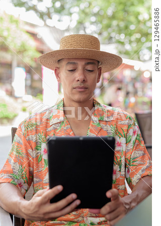 Hispanic Male Tourist Using Tablet Computer at Outdoor Cafe 129465886