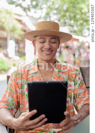 Hispanic Male Tourist Using Tablet Computer at Outdoor Cafe 129465887