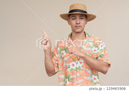 Smiling Hispanic Tourist Man Wearing Panama Hat and Tropical Hawaiian Shirt Pointing Finger Up 129465906