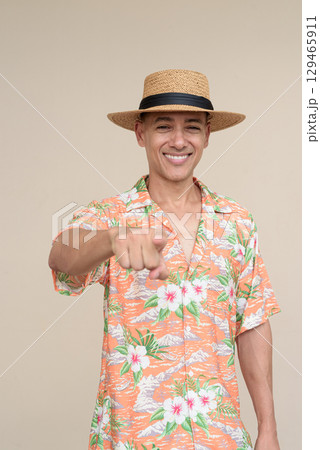 Smiling Hispanic Tourist Man Wearing Panama Hat and Tropical Hawaiian Shirt Pointing Finger Smiling Hispanic Tourist Man Wearing Panama Hat and Tropical Hawaiian Shirt Pointing Finger 129465911