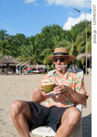 Hispanic man tourist sitting and using phone while having coconut water drink 129465937