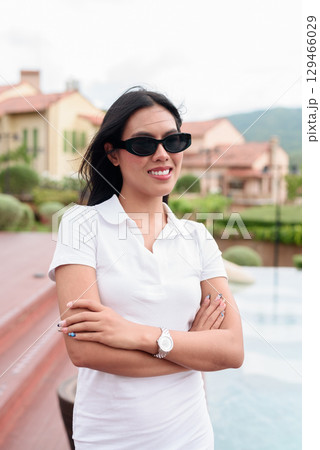 Asian woman in white polo shirt near swimming pool, outdoor nature, summer holiday portrait 129466029