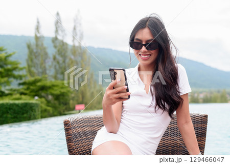 Asian woman in white polo shirt near swimming pool, outdoor nature, summer holiday portrait 129466047