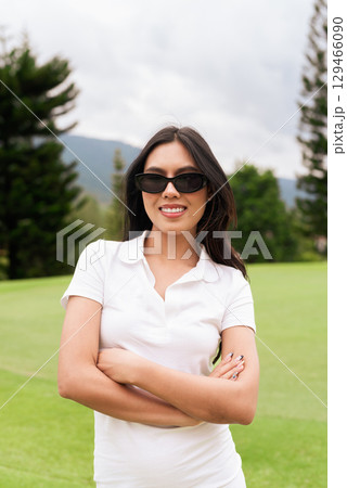 Asian woman in white polo shirt at golf course, on greenery field, tourist outdoor lifestyle 129466090