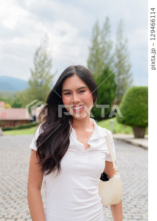 Asian woman walking wearing white polo shirt on European style city street summer fashion style 129466114