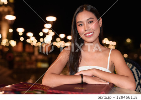 Asian woman in white polo shirt dining outdoors at night, evening dinner in casual travel lifestyle 129466118