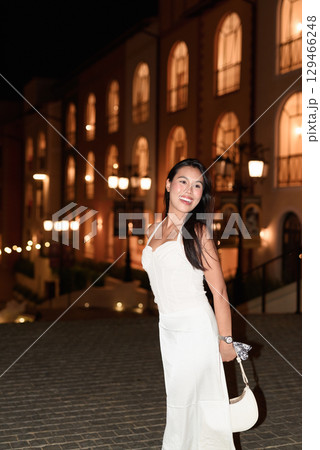 Young Asian woman tourist with long black hair in European style town at night Young Asian woman tourist with long black hair in European style town at night 129466248