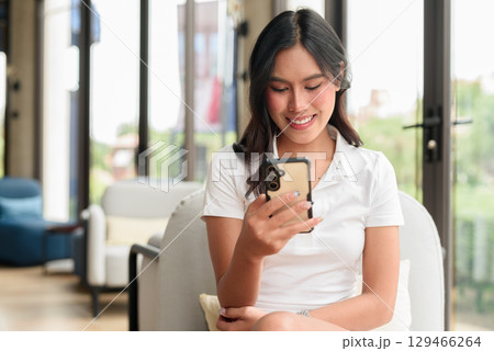 Young Asian woman in white polo shirt indoors, hotel lounge or cafe interior, tourist portrait Young Asian woman in white polo shirt indoors, hotel lounge or cafe interior, tourist portrait 129466264