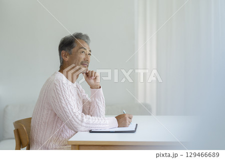 ペンを持って書き物をするシニア男性 129466689