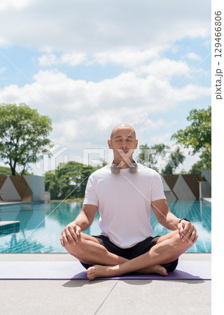 Man practicing yoga meditation by pool, wellness, mindfulness and healthy outdoor lifestyle concept Man practicing yoga meditation by pool, wellness, mindfulness and healthy outdoor lifestyle concept 129466806
