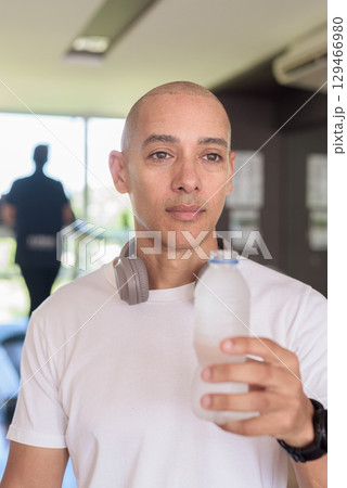 Man in gym drinking water after workout, fitness hydration and healthy lifestyle wellness concept 129466980