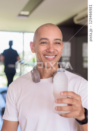 Man in gym drinking water after workout, fitness hydration and healthy lifestyle wellness concept 129466981