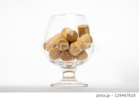A close-up shot of a clear glass snifter filled with several natural cork stoppers, isolated on a clean white background A close-up shot of a clear glass snifter filled with several natural cork stoppers, isolated on a clean white background 129467628