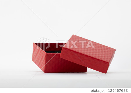 An open red gift box with its lid slightly askew, set against a clean white background An open red gift box with its lid slightly askew, set against a clean white background 129467688