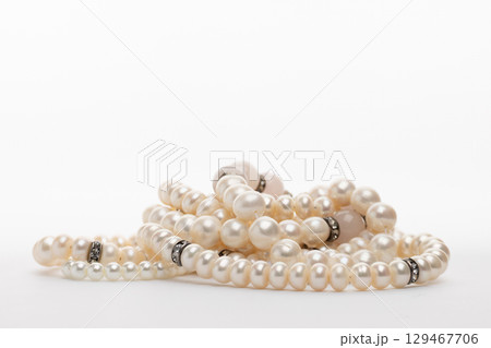 A luxurious strand of white pearls, elegantly draped and intertwined, featuring delicate silver or rhodium-plated A luxurious strand of white pearls, elegantly draped and intertwined, featuring delicate silver or rhodium-plated 129467706