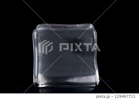 The ice cube is translucent with a slight sheen, suggesting a smooth, wet surface 129467711