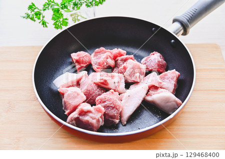 フライパンに入れた豚肩ロース肉 129468400