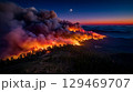 Wildfire raging across forested landscape at dusk, with thick smoke billowing into the sky, creating a dramatic atmosphere 129469707