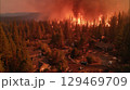 Wildfire raging through forested area, engulfing trees and threatening nearby homes, showcasing the destructive power of nature 129469709