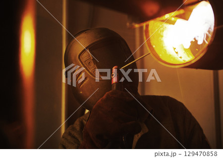 Male in face mask welds with welding 129470858