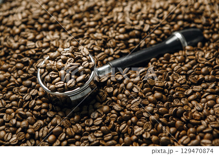Espresso Portafilter Filled With Coffee Beans Lies on Roasted Beans, Close-up. Concept of Espresso Serving. Espresso Portafilter Filled With Coffee Beans Lies on Roasted Beans, Close-up. Concept of Espresso Serving. 129470874