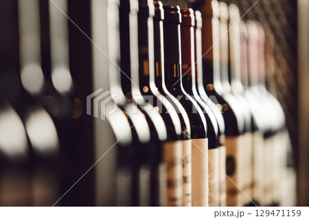 Close-Up View of Wine Bottles Lined Up on Cellar Shelf Highlighting Elite Alcohol Choices 129471159