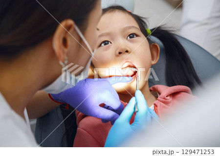 Child Girl Undergoing Routine Dental Check-Up With Female Dentist in Clinic 129471253
