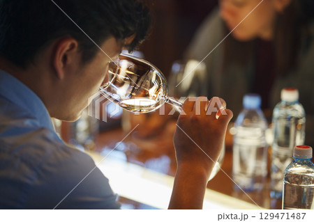 Man Sitting at Bar Drinking From Wine Glass 129471487