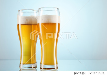 Yellow alcoholic fizzy drink, brew fills glasses to brim. Yellow alcoholic fizzy drink, brew fills glasses to brim. 129471494