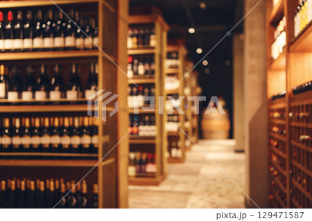 Blurred shot of big cellar in wine shop with wooden shelves for alcohol drinks. Long corridor of wine collection in elite alcoholic beverages. 129471587