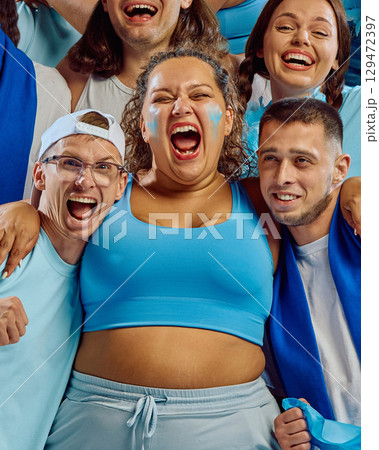 Group of fans embracing and cheering in blue sports outfits Group of fans embracing and cheering in blue sports outfits 129472397