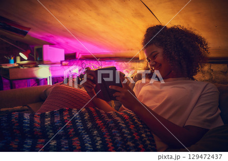 Teen girl reading on couch in retro attic space Teen girl reading on couch in retro attic space 129472437