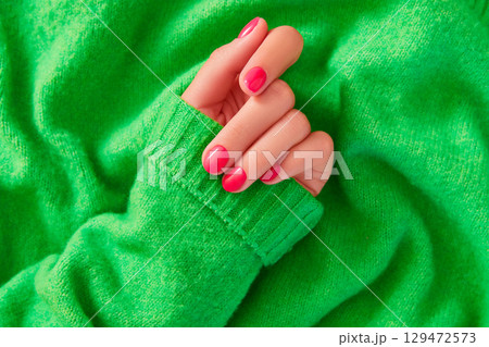 Beautiful womans hand with autumn winter pink nail design on green background. Manicure, pedicure beauty salon concept Beautiful womans hand with autumn winter pink nail design on green background. Manicure, pedicure beauty salon concept 129472573