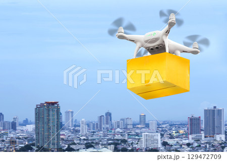 Drones flying through the air in sunset sky with a cardboard box package carrying clamped to send for customer. Futuristic delivery drone concept. 129472709