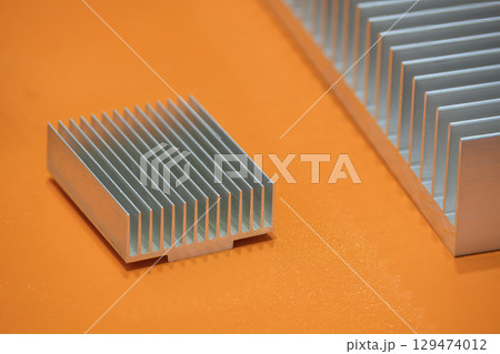 The aluminum heat sink parts on the orange background. The aluminum heat sink parts on the orange background. 129474012