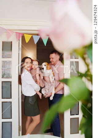 parents hold baby daughter in the doorway with a garland of colorful flags.  129474324